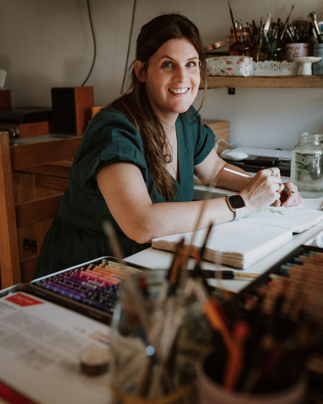 Selina sat at her art desk, smiling with an art brush in hand